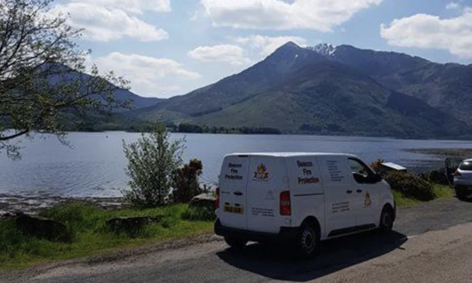 Beacon Fire Protection van parked by a loch with mountains behind